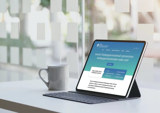 Svensk Värdepappersmarknads nya webbplats visas i en ipad som står på ett bord med en kaffemugg bredvid