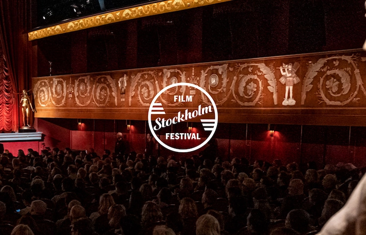 En bild på en fullsatt, något upplyst biosalong med Stockholms filmfestivals:s logga mitt i bilden.