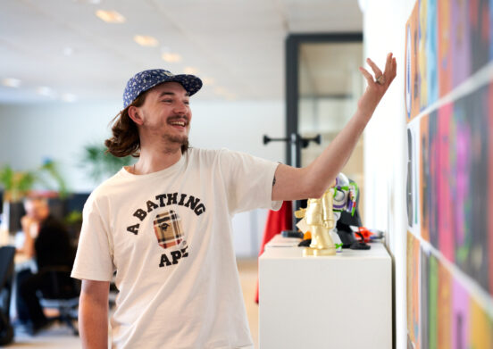 En medarbetare iklädd vit t-shirt som betraktar en färgglad väggmålning eller konstverk under en inspirationsdag